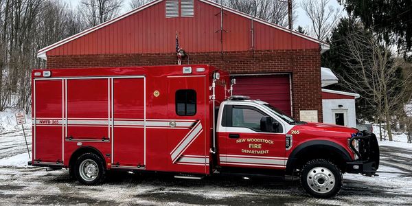 Red fire department rescue truck parked outside a brick building.