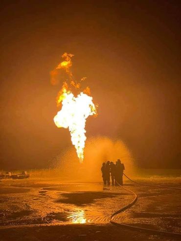 Firefighters battling a large fire at night.