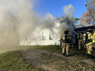 Firefighters respond to a house fire with heavy smoke.