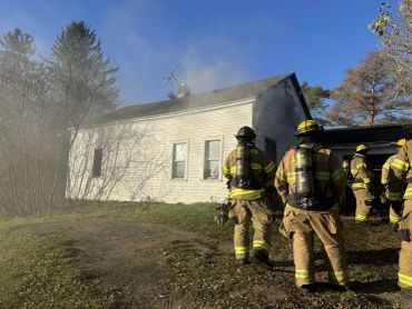 Firefighters approach a smoke-filled white house.