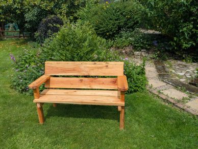 A wooden bench on green grass in a garden.