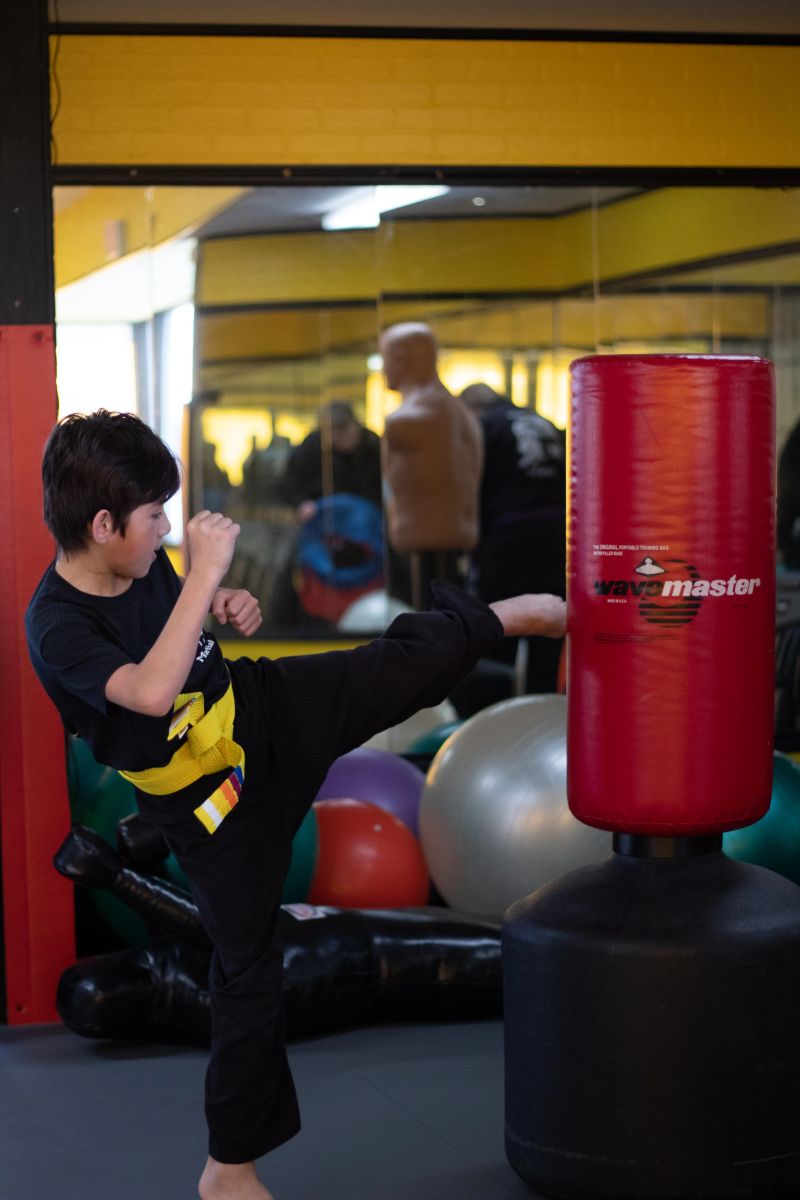 Student driving a kick into the heavy bag