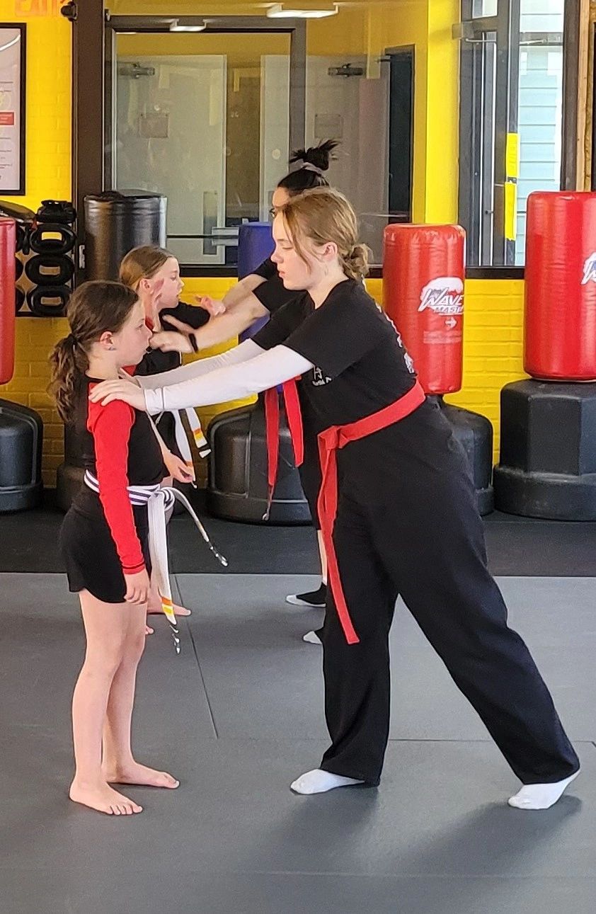 Instructor coaching a young student through a self-defense technique