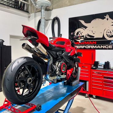 Red sport motorcycle on a blue lift in a garage with red tool cabinets.