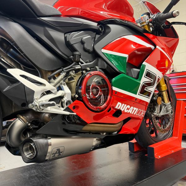 Close-up of a red Ducati Corse motorcycle with custom exhaust and Italian flag decals.