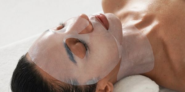 Woman relaxing with a transparent facial mask on her face.