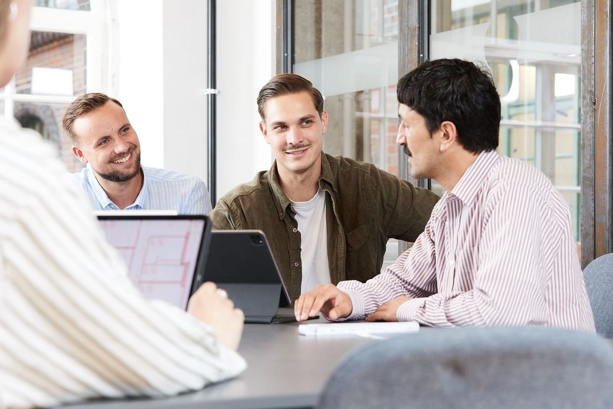 Drei Männer in einem Meeting lächeln und diskutieren.