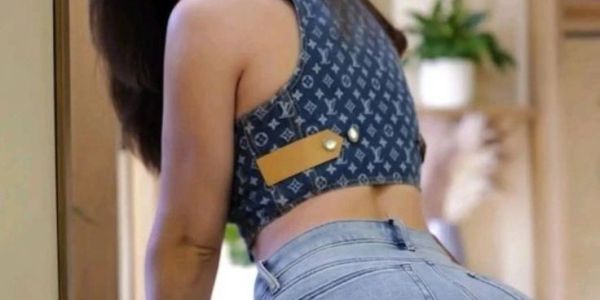 Woman posing in denim jeans and a designer crop top indoors.