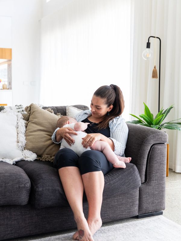 woman sitting on a couch breastfeeding her baby