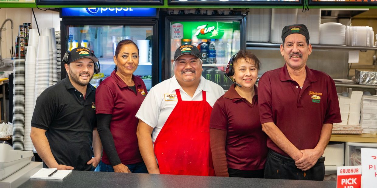 People along with two ladies standing at the counter