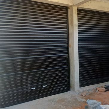 Two black metal roller shutters on a building under construction.