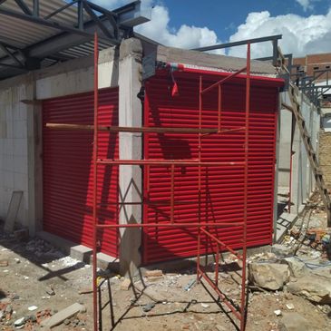 Red metal shutters on a partially constructed building with scaffolding around.