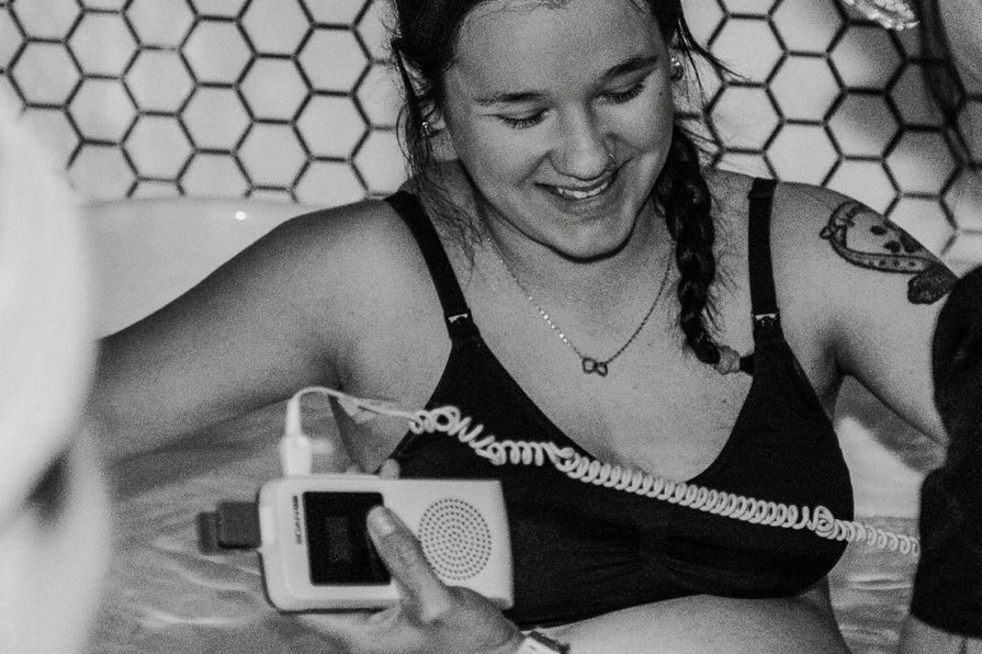 A pregnant woman in a birthing tub, supported by two people during labor.