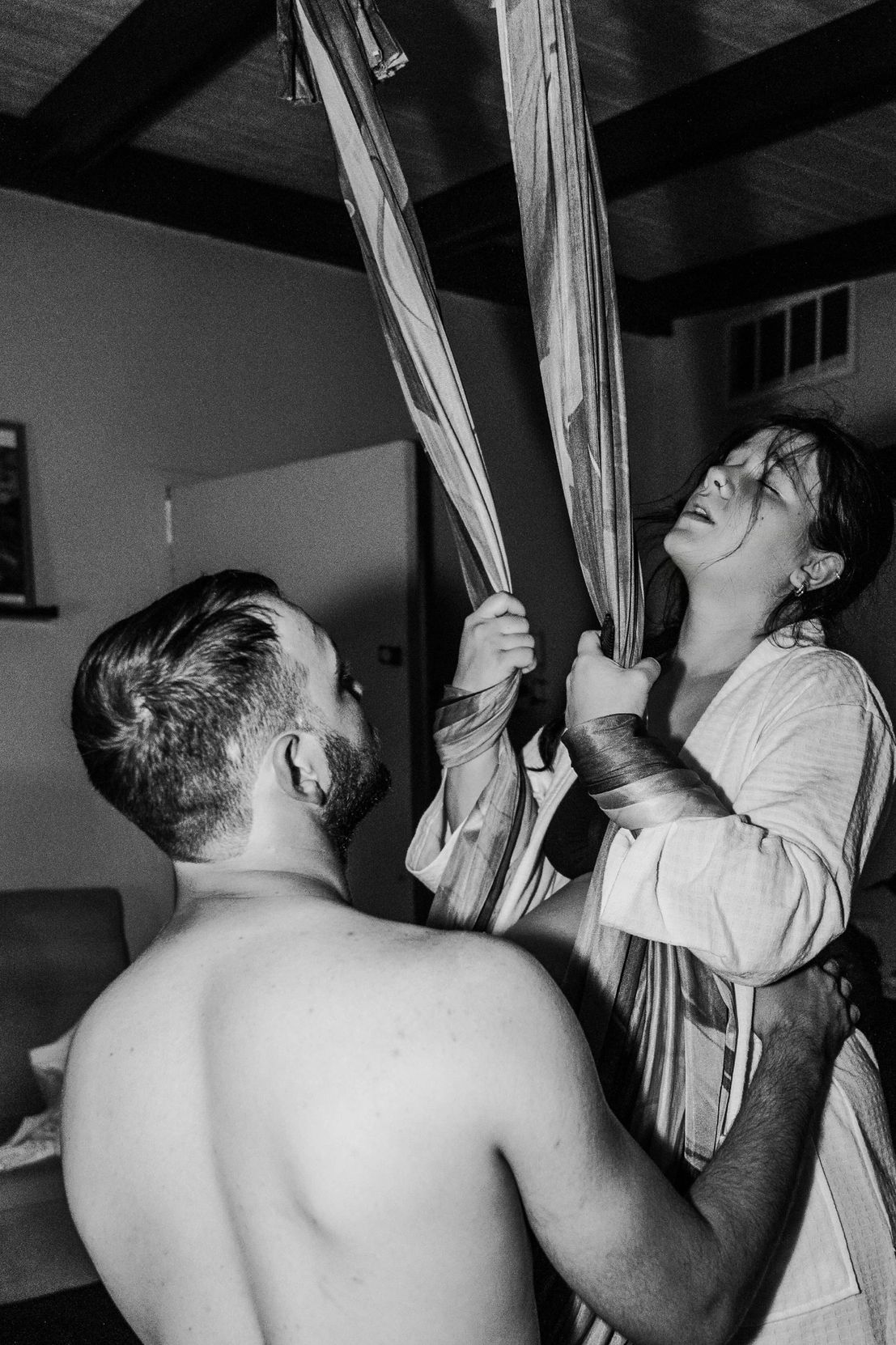 A woman in labor is supported by a man and a medical professional in a home setting.