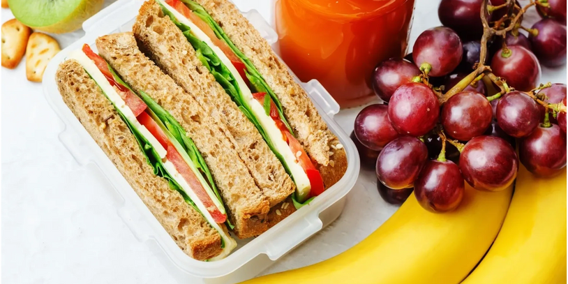 corporate lunch - sandwich with kiwifruit banana and grapes and a bottle of juice