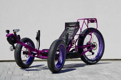 A purple recumbent tricycle with three wheels.