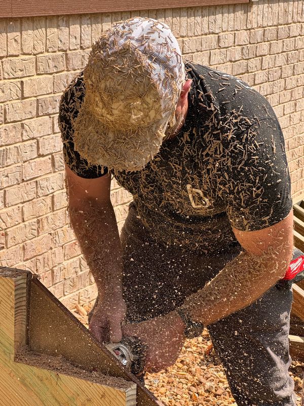 Carpenter routing a composite decking fascia board for a stair stringer.