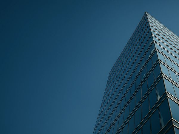 Modern glass skyscraper against a clear blue sky.