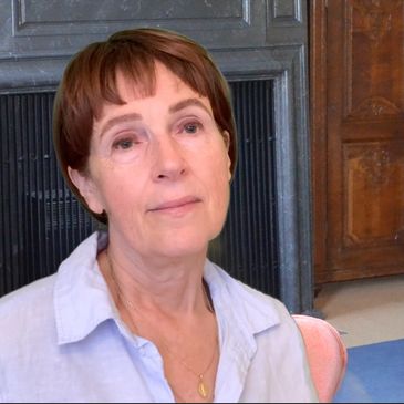 A thoughtful woman with short hair sitting indoors.