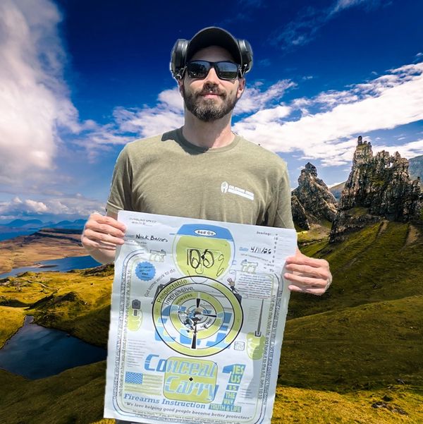 Man holding a shooting target in a scenic mountainous area.