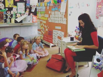 Teacher reading a book to young children in a classroom.