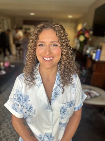 Smiling woman with curly hair in a floral shirt.