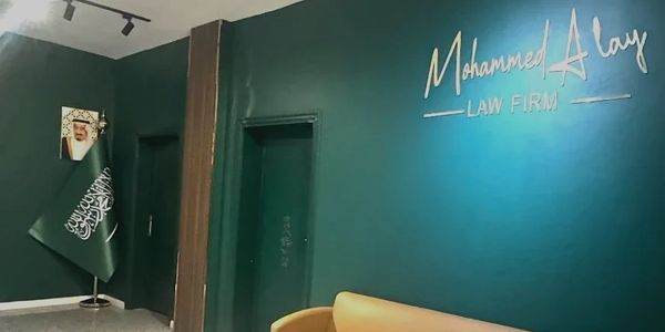 Reception area of Mohammed Alay Law Firm with Saudi flag and portrait.