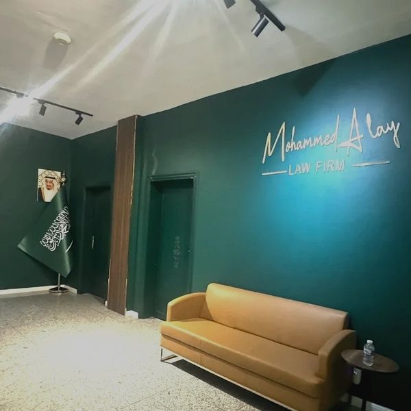 Reception area of Mohammed Alay Law Firm with Saudi flag and portrait.