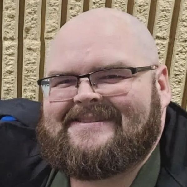 Smiling bald man with glasses and a thick beard.
