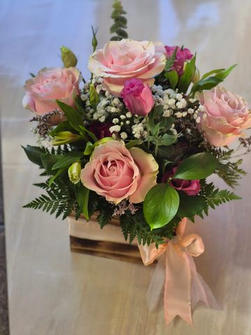 Elegant bouquet of pastel roses with greenery in a wooden box.