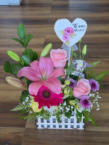 Colorful floral arrangement with a heart-shaped card saying 'Te amo Mamá'.
