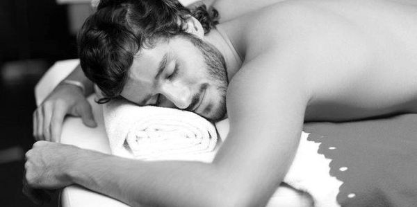 A man peacefully resting on a massage table with a towel under his head.
