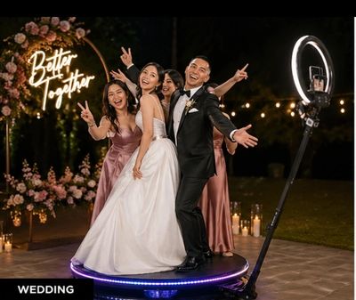 Happy bride, groom, and bridesmaids posing on a platform at night.