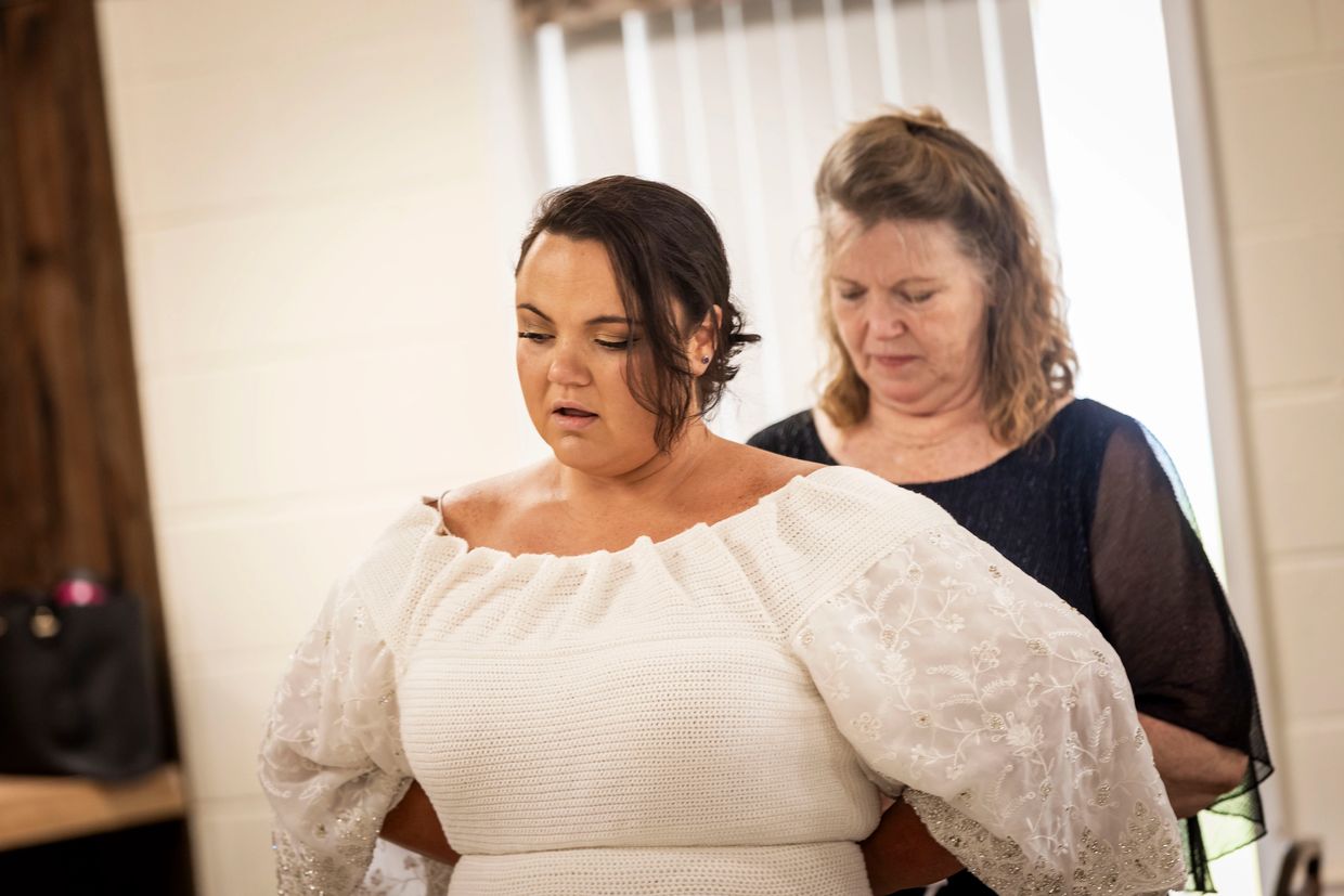 Woman helping another woman with her dress.