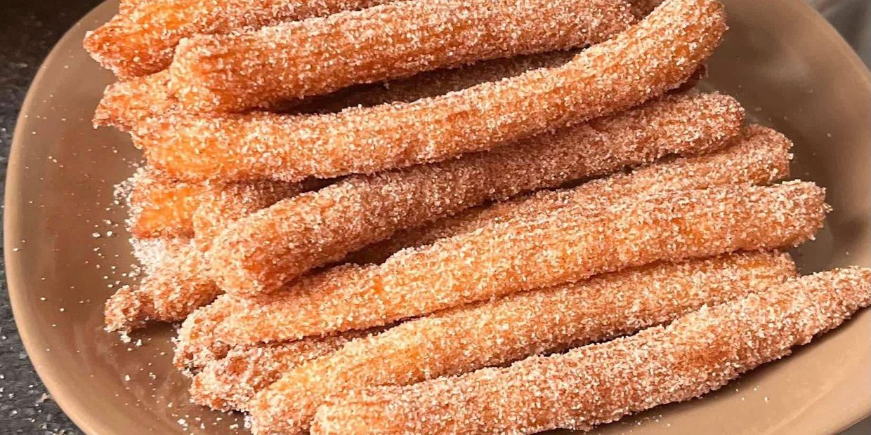 A plate of sugar-coated churros stacked neatly.