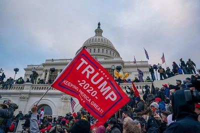 A red Trump 2020 banner is waved by protestors outside the capitol building on the day of the Januar