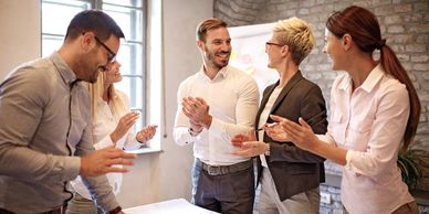 A group of people clapping whilst standing around a table