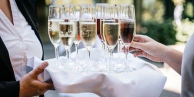 A tray of champagne glasses being offered to a guest