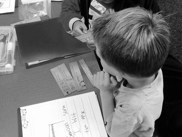 A child working on a reading activity with an adult's assistance.