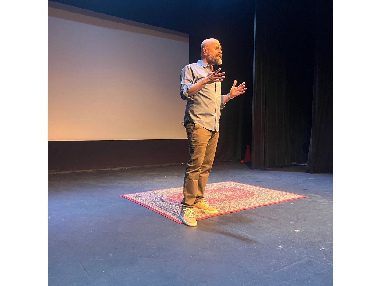 Haig "Hike" Chahinian in blue untucked shirt and khaki pants gestures with his hands open.