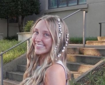 Smiling young woman with long blonde hair and decorative pearl strands.