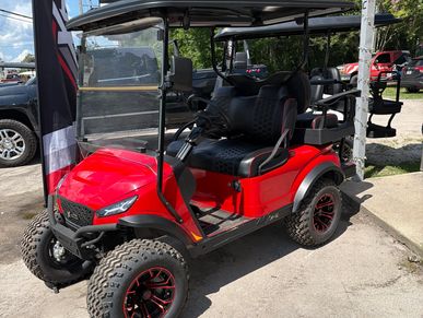 Red off-road golf cart with rugged tires and black cushioned seats.