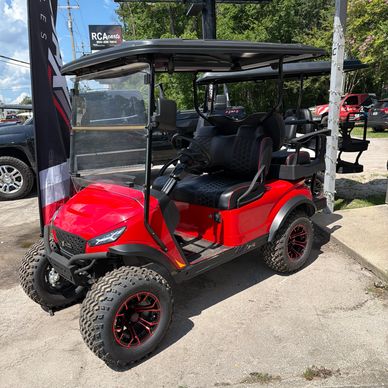 Red off-road golf cart with rugged tires and black cushioned seats.