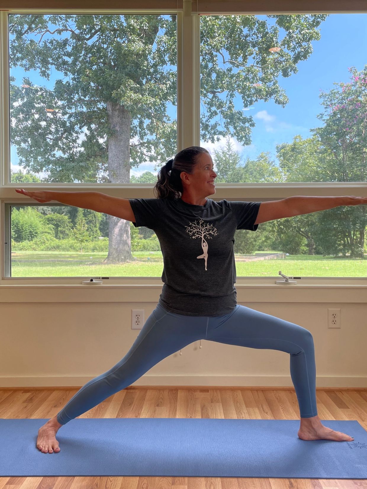 Woman practicing yoga indoors with a scenic window view.