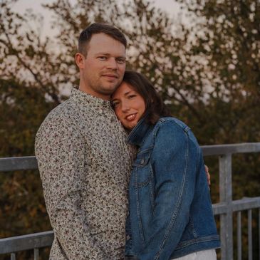 Couple embracing outdoors, holding hands with affectionate smiles.