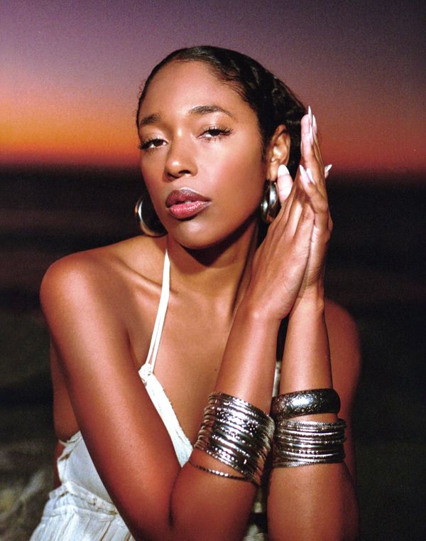 Woman posing with folded hands at sunset, wearing silver bangles.