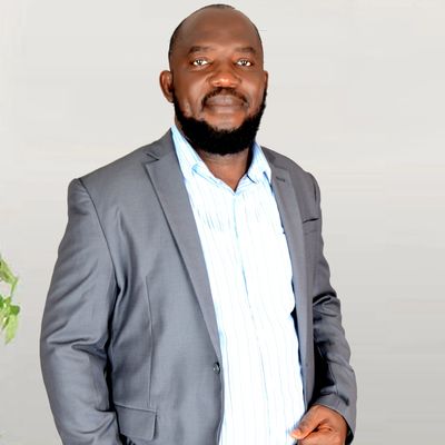 Ben Akponine-Samuel wearing a grey suit with blue shirt facing the camera. Author photo for THP.