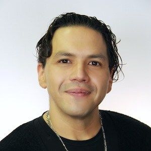 Portrait of a smiling man with dark hair and a black shirt.