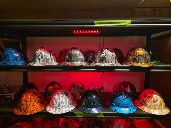 Decorative hard hats on shelves with colorful designs and lighting.