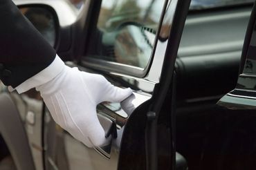 DE Chauffeurs Mercedes Benz E Class chauffeur opening the door